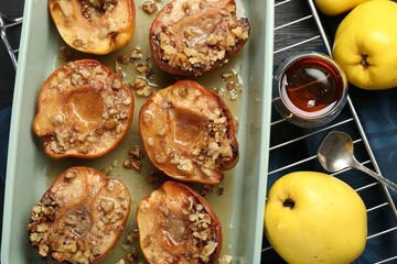 Tasty baked quinces with nuts and honey in dish on table, flat lay