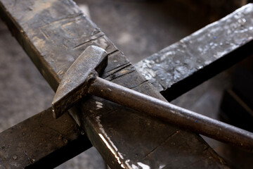 A metal hammer used for forging iron stands on an iron floor in a metal workshop in Turkey