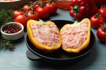 Raw stuffed peppers with ground meat and ingredients on light blue wooden table