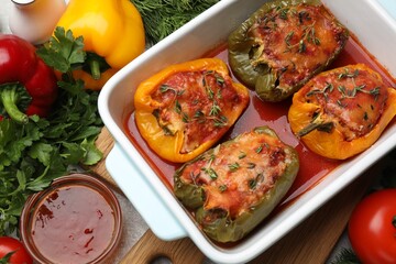 Tasty stuffed peppers in dish and ingredients on grey table, flat lay