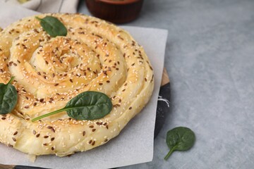 Delicious puff pastry with spinach on grey table, closeup