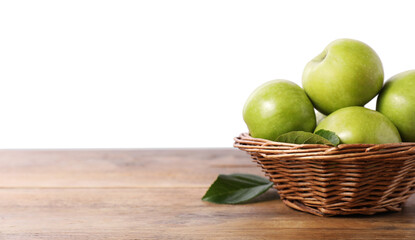 Ripe green apples in wicker basket on wooden table against white background. Space for text