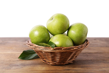 Ripe green apples in wicker basket on wooden table against white background