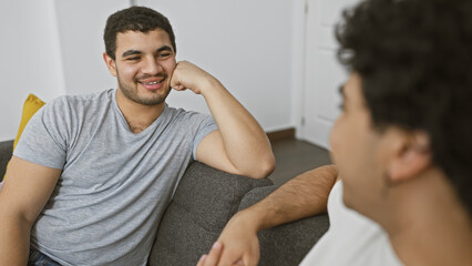 Two men relax on the couch, engaging in a friendly conversation, embodying warmth and connectivity in a casual home setting.