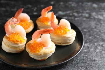 Delicious puff pastry with shrimps, cream cheese and red caviar on dark table
