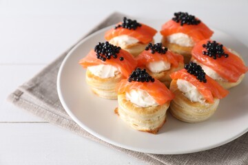 Delicious puff pastry with cream cheese, salmon and black caviar on white wooden table