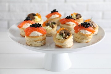 Different delicious puff pastry snacks on white wooden table