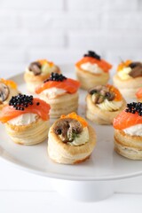 Different delicious puff pastry snacks on stand