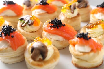 Different delicious puff pastry snacks on plate, closeup