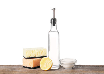 Natural cleaning products. Vinegar in bottle, baking soda, lemon and sponges on wooden table against white background