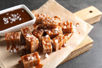 Tasty candies, caramel sauce and salt on grey table, closeup