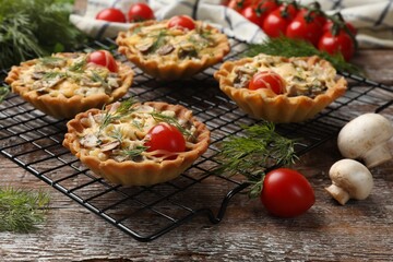 Tasty tartlets with cheese, tomatoes, mushrooms and dill on wooden rustic table, closeup