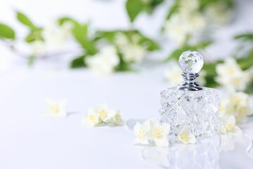 Aromatic perfume in bottle and beautiful jasmine flowers on white background, space for text