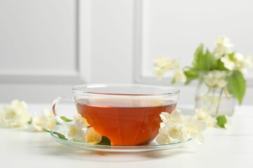 Hot jasmine tea in cup and flowers on white marble table