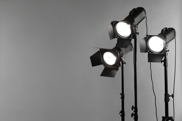Grey photo background and professional lighting equipment in studio. Space for text