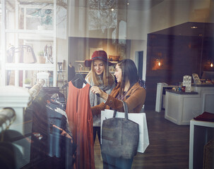 Smile, customer and women with dress in boutique shop for promotion, sale and discount. Happy, female friends and people checking rack of clothes in fabric, fashion and retail store at indoor mall