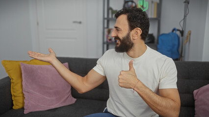 Obraz premium Bearded man in casual attire giving a thumbs-up in a modern living room setting.