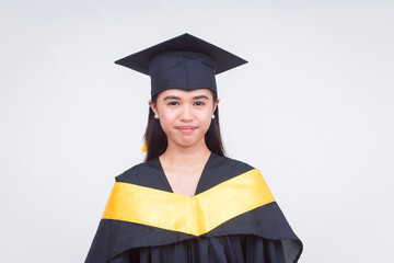 Portrait of a young college graduate in cap and gown, smiling slightly, isolated on a white...