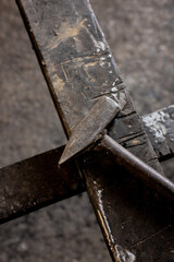 A metal hammer used for forging iron stands on an iron floor in a metal workshop in Turkey