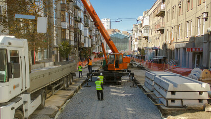 Fototapeta premium Unloading concrete plates from truck by crane at road construction site timelapse.