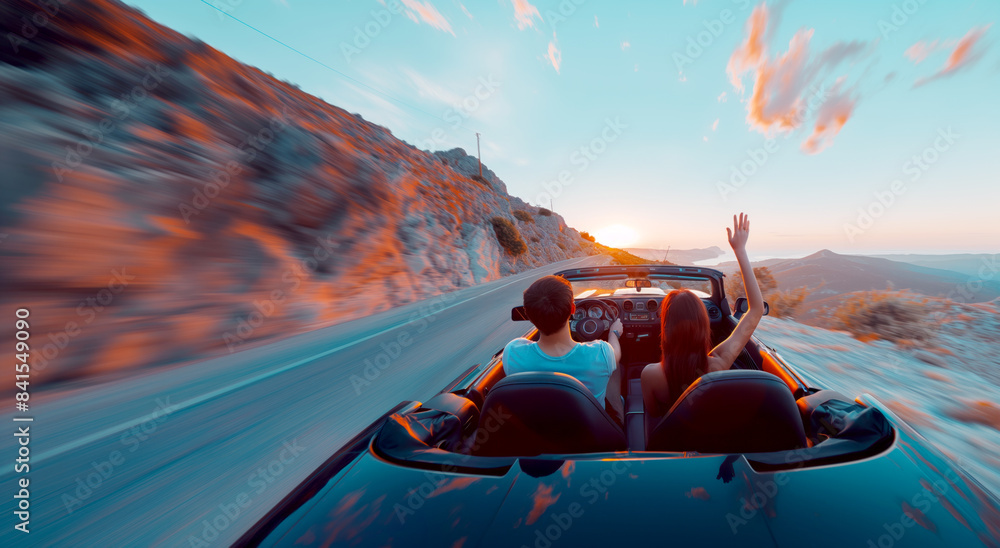 Wall mural couple in a convertible car enjoying a sunset drive, motion blur effect, with a mountainous backgrou