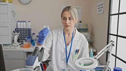 Naklejka premium Focused young woman scientist analyzing a specimen in a modern laboratory setting