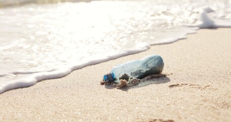 Beach, ocean and plastic bottle in sand for pollution, litter and trash in sea for global warming crisis. Nature, climate change and closeup of garbage in sea to reduce waste, recycling and cleaning