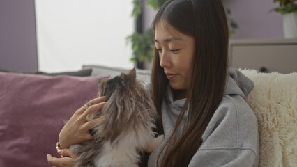 Young chinese woman lovingly interacting with her pet cat in a cozy indoor apartment setting