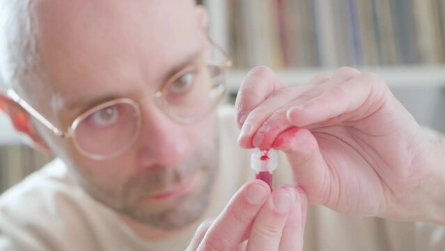 man pricking finger and collecting blood in tube for self-administered medical rapid test, Personal health data, closeup fingers and action