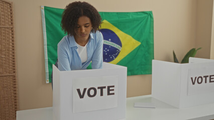 A young african american woman with curly hair is voting in an electoral college room with a...