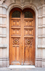 A wooden door with a handle in the wall of the house in close-up - Barcelona, Spain