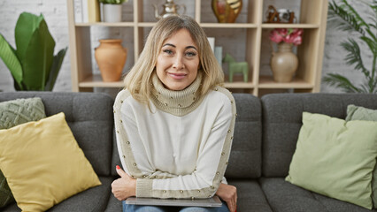 Obraz premium A caucasian adult woman with blonde hair smiling comfortably in a cozy living room setting, showcasing a friendly and mature aura.