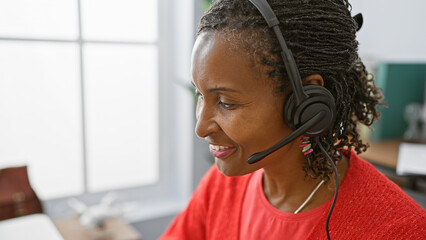 African american woman with headset smiling in an office setting, representing professional and cheerful customer service