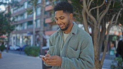 Smiling african american man using smartphone in urban setting © Krakenimages.com
