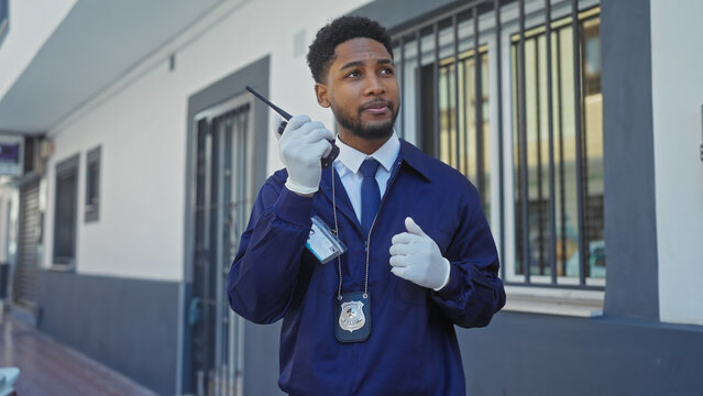African american security officer standing on the city street, communicating via radio, portraying vigilance and professionalism.