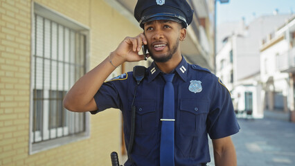An african american police officer talking on his radio with a city street in the background.