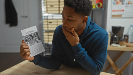 A pensive african american man reviews a missing person flyer in a police department setting, symbolizing investigation.
