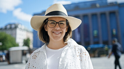 Beautiful young hispanic woman smiling confident wearing summer hat at Nobel prize building