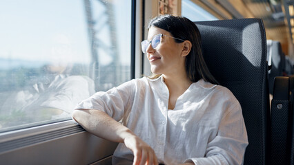 Young beautiful hispanic woman smiling happy looking through the window inside train wagon