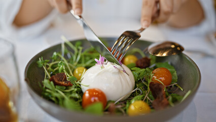 Young woman mixing burrata salad at the restaurant