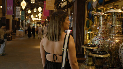 A young adult hispanic woman explores a traditional souk in dubai, intrigued by the exotic arab wares. © Krakenimages.com