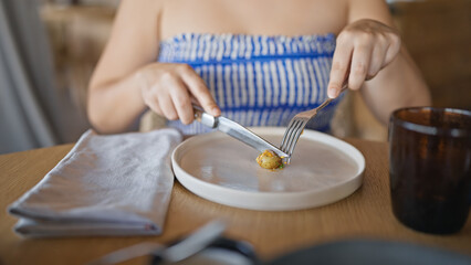 Young hispanic woman eating potatoes at the restaurant