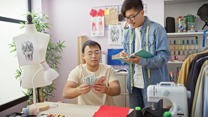 Two men collaborating in a tailor shop with one counting yuan and the other taking notes amidst design sketches and a mannequin.