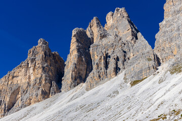 Dolomites beautiful alpine rock tower summits under blue sky in summer. Italian Alps mountains scenic landscape of rocky climbing walls in the high altitude majestic view of the cliff and green valley