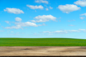 Table background against the backdrop of a summer field. Wooden table display for and rustic sunny agricultural landscape with meadow and sky