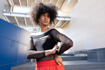 Young Afro Latino non binary person posing in black and red clothing.