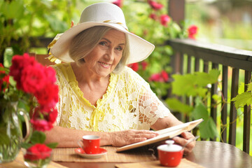 Happy aged woman drinking coffee and talking on phone