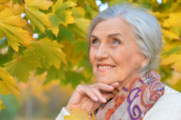 Senior nice woman walking in the park in autumn. 