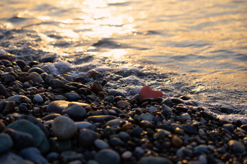 red stone in  shape of heart on  beach by  sea