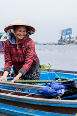 Obraz premium Vietnamese woman with conical hat working on her boat on the Mekong river